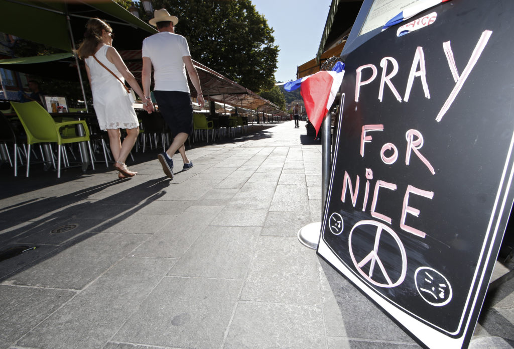 A couple walk through the empty flower market in the old city and near a sign which reads, Pray for Nice days after a truck attack on the Promenade des Anglais on Bastille Day killed scores and injured as many in Nice, France, July 17. (Photo: ERIC GAILLARD/REUTERS/Newscom)