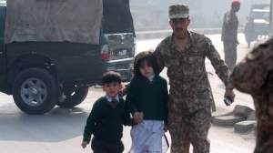 A soldier escorts schoolchildren from the Army Public School that is under attack by Taliban gunmen in Peshawar