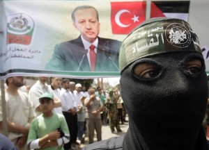 A masked member of Hamas stands in front of a banner during a protest in Central Gaza Strip